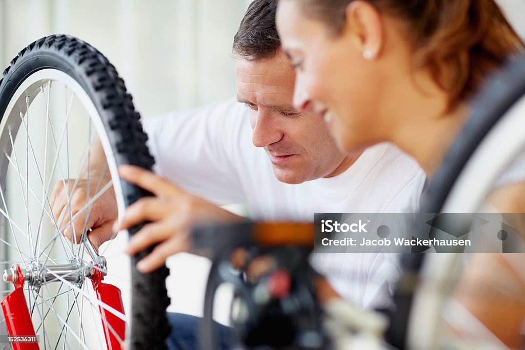 Medio de hombre arreglando un neumático con esposa bicicleta - Foto de stock de Bicicleta libre de derechos