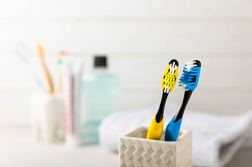 Close-up of a set of multicolored toothbrushes in a glass on a gray background.Dentistry concept.Oral care. The concept of cosmetic products for the bathroom.Side view, copy space.Dental hygiene