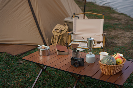 Outdoor activity concept, Camping area with tent and equipment for camping on the table near lake.