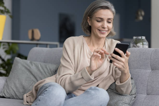 istock Cheerful pretty grey haired woman typing message 1525380411
