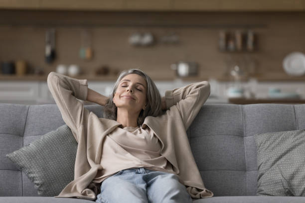 istock Happy grey haired woman resting on couch with closed eyes 1525380425