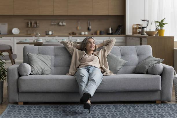 istock Happy dreamy calm grey haired woman resting on comfortable sofa 1525380430