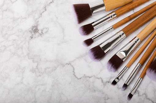Makeup brushes on a white marble background. Collection of cosmetic makeup brushes. Beautyconcept. Makeup tool. Place for text. Place to copy.