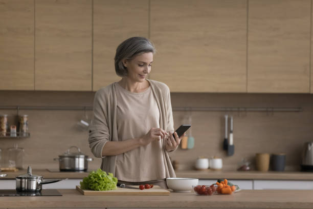 istock Positive mature chef blogger woman using smartphone over table 1525387580
