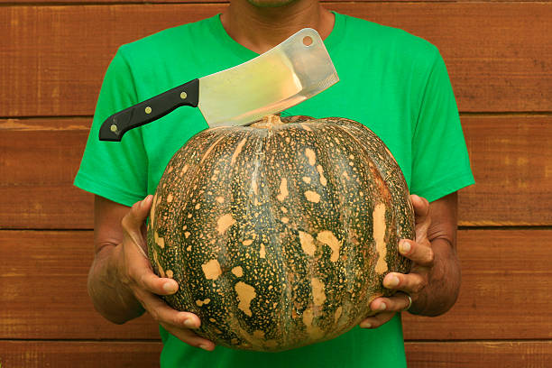 Man chef holding pumpkin and cleaver knife stock photo