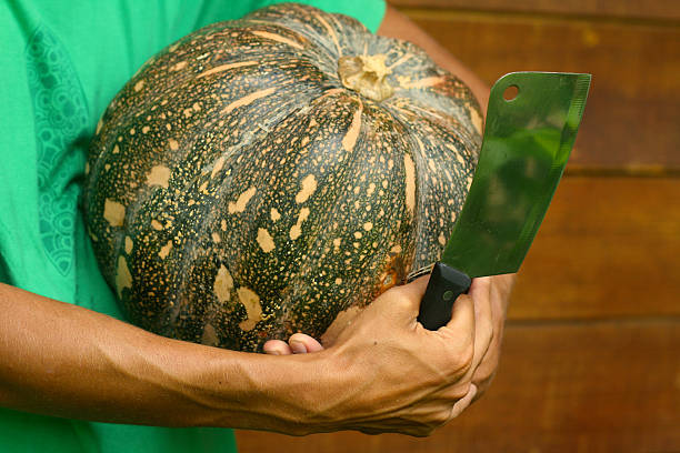 Man chef holding pumpkin and cleaver knif stock photo