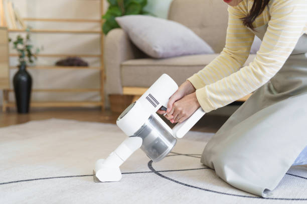 maid vacuuming on the carpet with handheld cordless vacuum cleaner for cleaning dust in living room - appliance living room domestic room lifestyles imagens e fotografias de stock