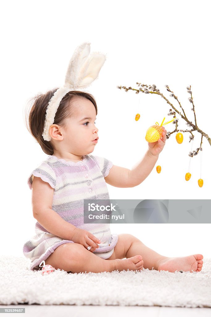 Little bunny girl Baby girl in easter bunny costume, playing with yellow easter egg decoration. Isolated on white background. Click here for more Baby photos: Baby - Human Age Stock Photo