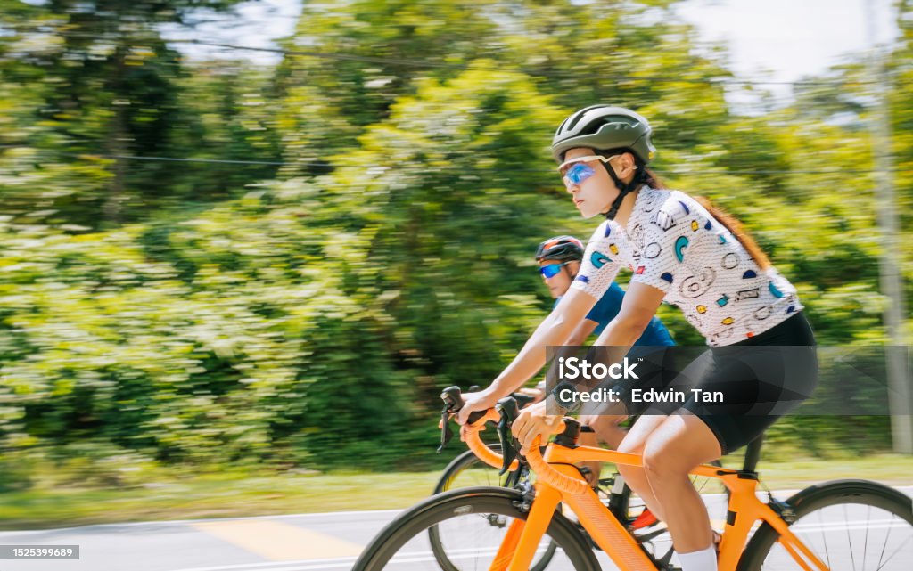 Asian Chinese female cyclist leading in rural cycling event Chinese Ethnicity Stock Photo