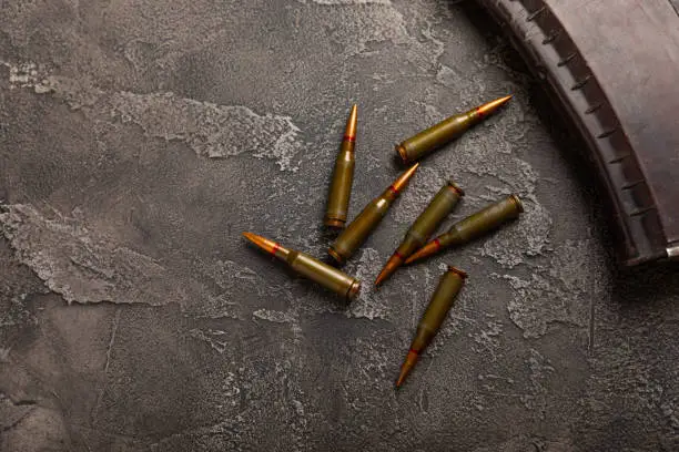 Photo of Bullets and ammo magazine with kolashnikov assault rifle on texture marble.Composition with place for text.Rifle and carbine cartridges on wooden background.Military concept.Copy space