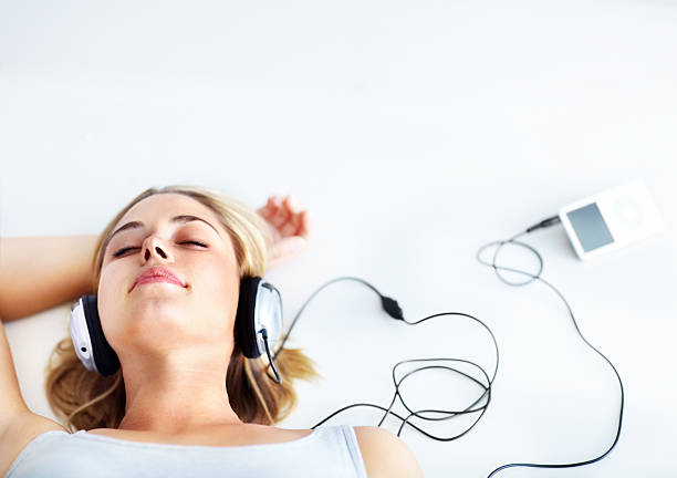 Closeup Portrait of Beautiful White Woman Smiling While Putting on her Headphones in the Park During her Early Morning Walk. Female Teenager Enjoying Music and Fresh Air While Being Outdoors