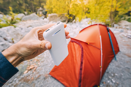 Powerbank for charging smartphone and other electrical devices during weekend in hike. Orange tent in background