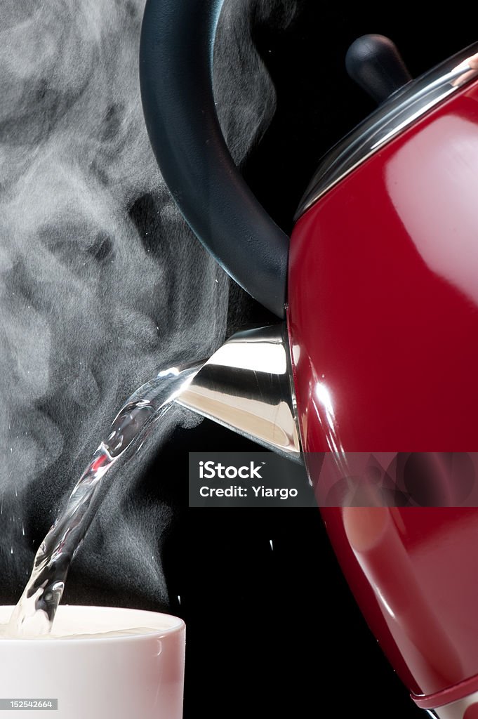 Boiling water Studio. Water runing from kettle to cup. No filtering. Steam highlighting. Black Color Stock Photo