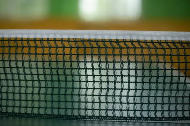 Photo of Table tennis net. Tennis table. Mesh is stretched across table.