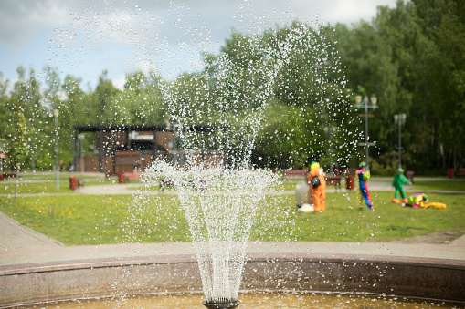 Fountain in park. Water in park. Spray of fountain. Summer view of city recreation area. Water drops.