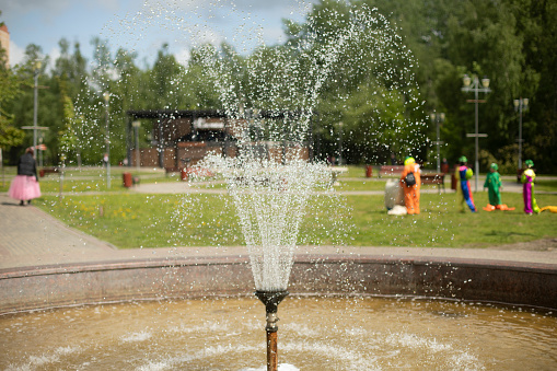 Fountain in park. Water in park. Spray of fountain. Summer view of city recreation area. Water drops.