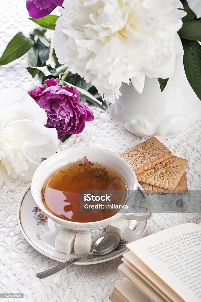 Du thé avec des biscuits le livre et de fleurs - Photo de Arbre en fleurs libre de droits