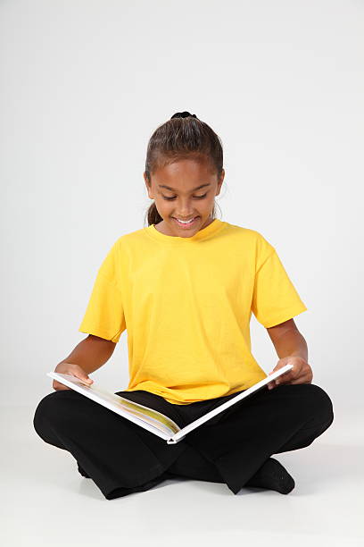istock Smiling school girl 10 sitting reading a book studio shot 152545522