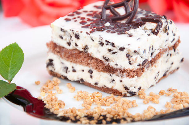 Sweet chocolate dessert with nuts on plate and rose on background