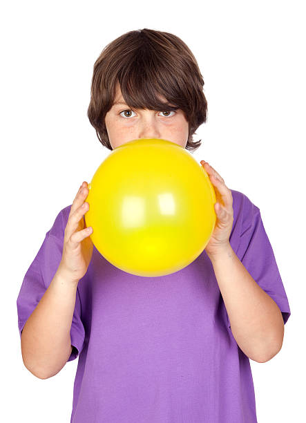 divertido niño soplando un globo de color amarillo - balloon blowing inflating child fotografías e imágenes de stock