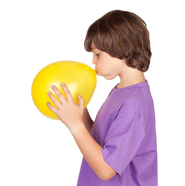 divertido niño soplando un globo de color amarillo - balloon blowing inflating child fotografías e imágenes de stock