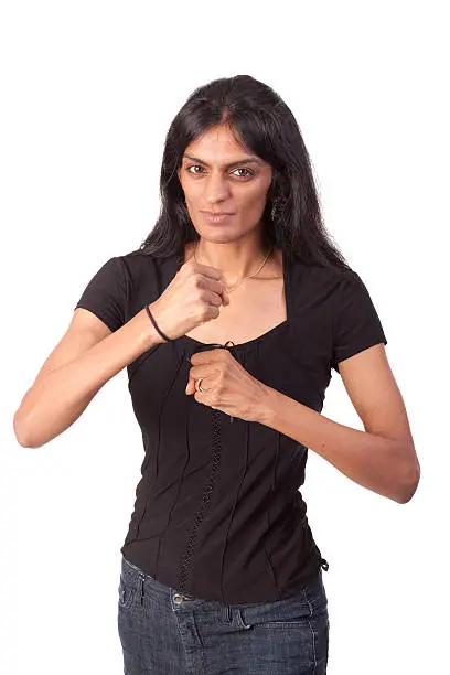 An attractive Indian woman holding her clenched fists up as if she's ready for a fight.