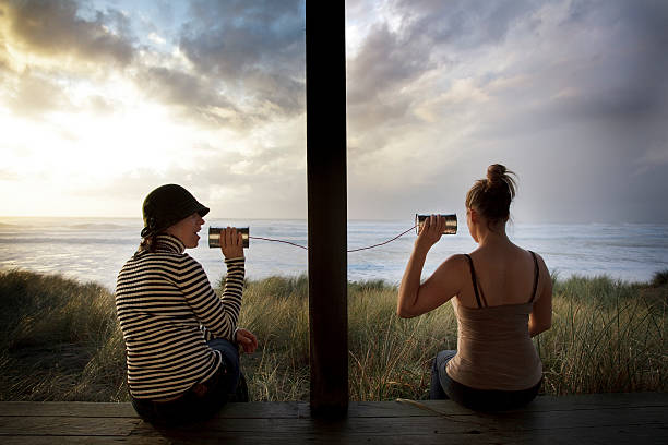 Two Girls Talking on Cans