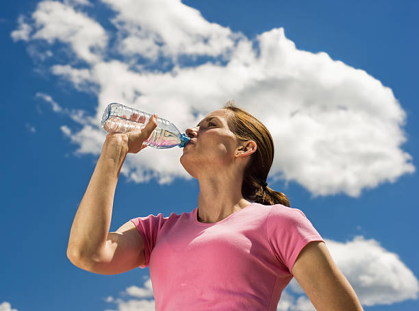 Frau trinkt Mineralwasser mit blauem Himmel – Foto