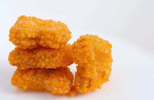 Pile of golden deep-fried and tasty chicken nuggets isolated on white background