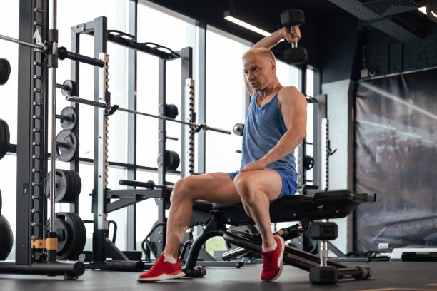 istock Muscular man working out in gym doing exercises with dumbbell at triceps. 1525540021