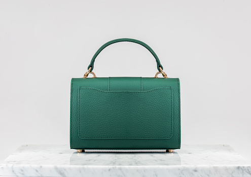 Women 's bag. Luxury, green leather handbag on white background, on marble floor. A elegant bag is see from back side. Fashionable trendy.