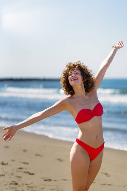 istock Smiling woman standing on sandy beach in daylight 1525679294