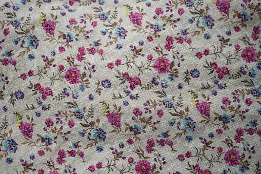 Cute linen fabric with a floral pattern, pink and blue flowers on a beige material.