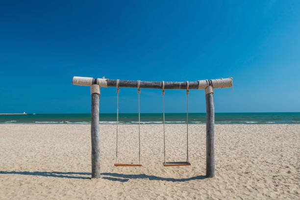 istock wooden swing on white sand beach against blue sky, Cha Am 1525849549