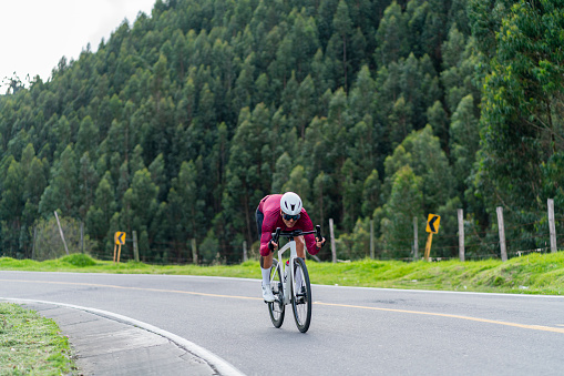 Latino man of average age of 45 years dressed in cycling clothing, helmet and goggles is riding his professional bicycle cycling on the roads of the towns outside of Bogota