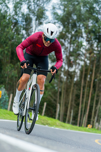 Latino man of average age of 45 years dressed in cycling clothing, helmet and goggles is riding his professional bicycle cycling on the roads of the towns outside of Bogota