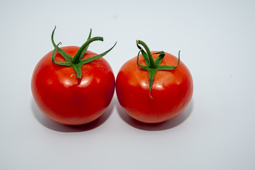 Two fresh tomatoes on a white background