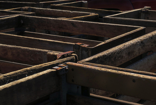 close up of a large number of backlit wooden plank crates, stored outside to hold merchandise at a junkyard, Long Island, New York