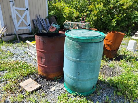Some oil and weathered fuel barrels sitting on a lawn.
