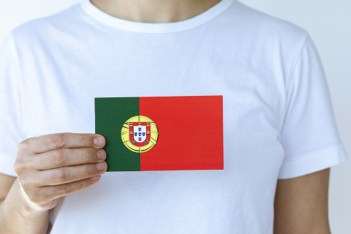 Hand is showing flag of Portugal to camera.