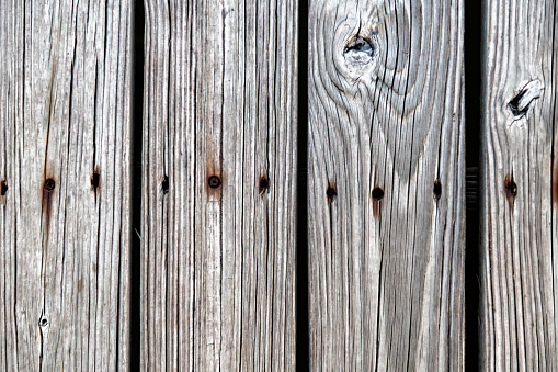 Wooden planks exposed to the weather nailed to make either a deck floor or a fence.