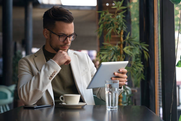 istock Serious businessman using digital tablet sitting at table in a Cafe 1526199255