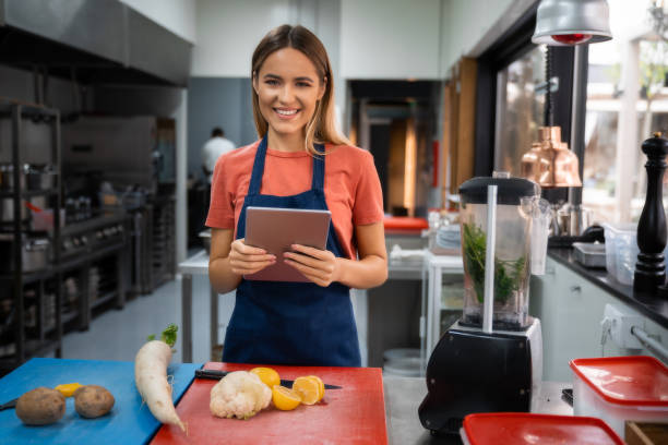 istock Beautiful young female chef looking at camera holding digital tablet 1526203407