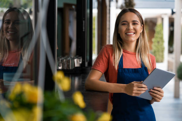 istock Smiling confident young woman wearing apron looking at camera holding digital tablet 1526204448