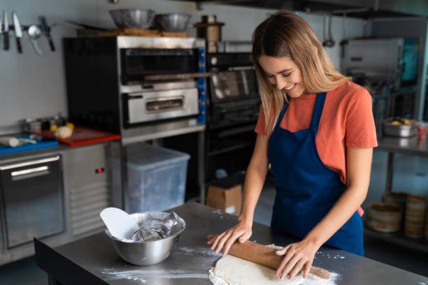 istock Young cheerful woman working in bakery kitchen, preparing dough to bake 1526205103