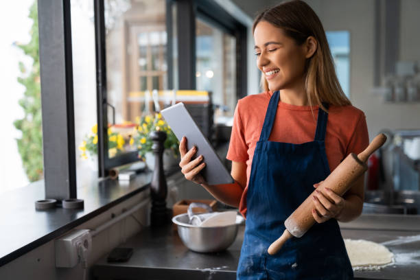 istock Beautiful satisfied young woman using digital tablet managing a pastry shop 1526206545
