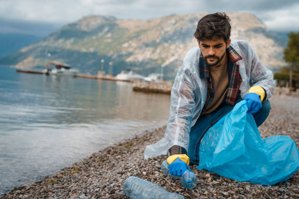 istock Humanitarian young man picking up recyclables from sea shore 1526216299