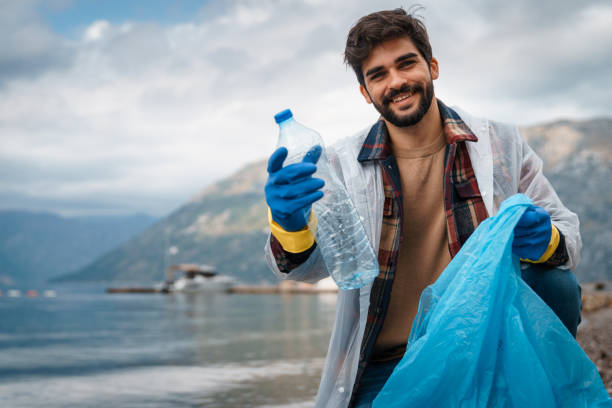 szczęśliwy uśmiechnięty mężczyzna sprząta plażę - environmental conservation recycling thinking global warming zdjęcia i obrazy z banku zdjęć