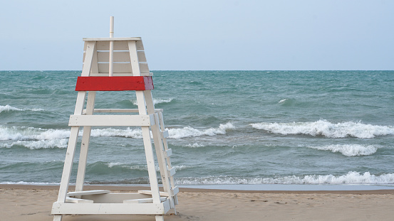 Empty lifeguard chair facing choppy waters on Lake Michigan when the water at Gillson Beach is closed due to high winds and riptides.