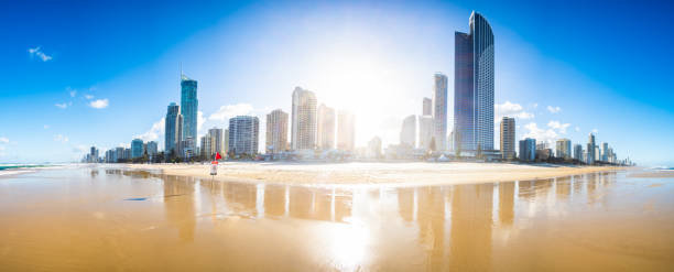 Backlit by the sun wide panorama view of Surfers Paradise, Gold Coast from the beach with no people and reflections of the buildings on the beach.